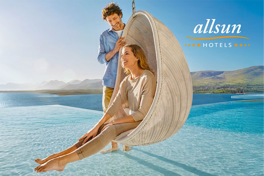 Frau in Muschel Schaukel über einem Pool, Mann steht dahinter mit Füßen im Wasser